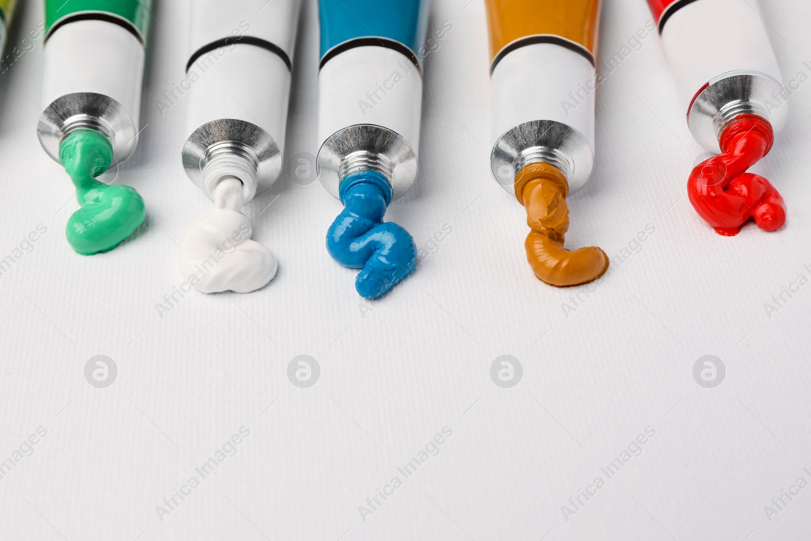Photo of Tubes with oil paints on white canvas, closeup. Space for text