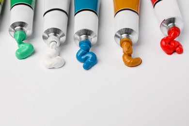 Tubes with oil paints on white canvas, closeup. Space for text