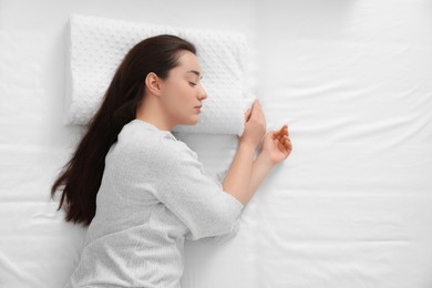 Photo of Woman sleeping on memory foam pillow, top view. Space for text