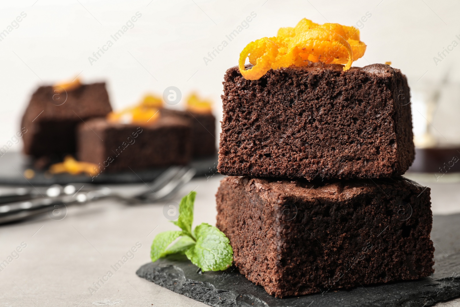 Photo of Fresh brownies decorated with orange peel and mint on table, space for text. Delicious chocolate pie