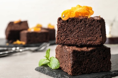 Photo of Fresh brownies decorated with orange peel and mint on table, space for text. Delicious chocolate pie