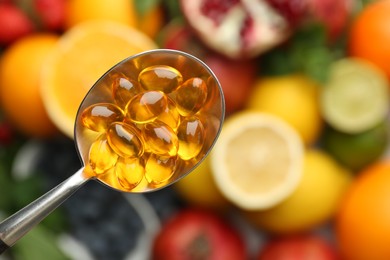 Photo of Vitamin pills in spoon over fresh fruits, top view. Space for text