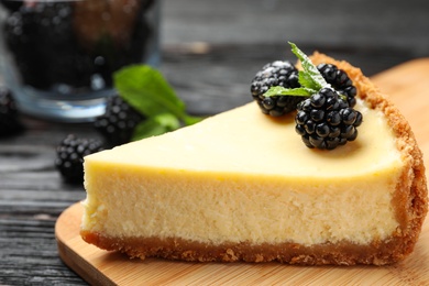 Photo of Piece of delicious cheesecake with blackberries on table, closeup