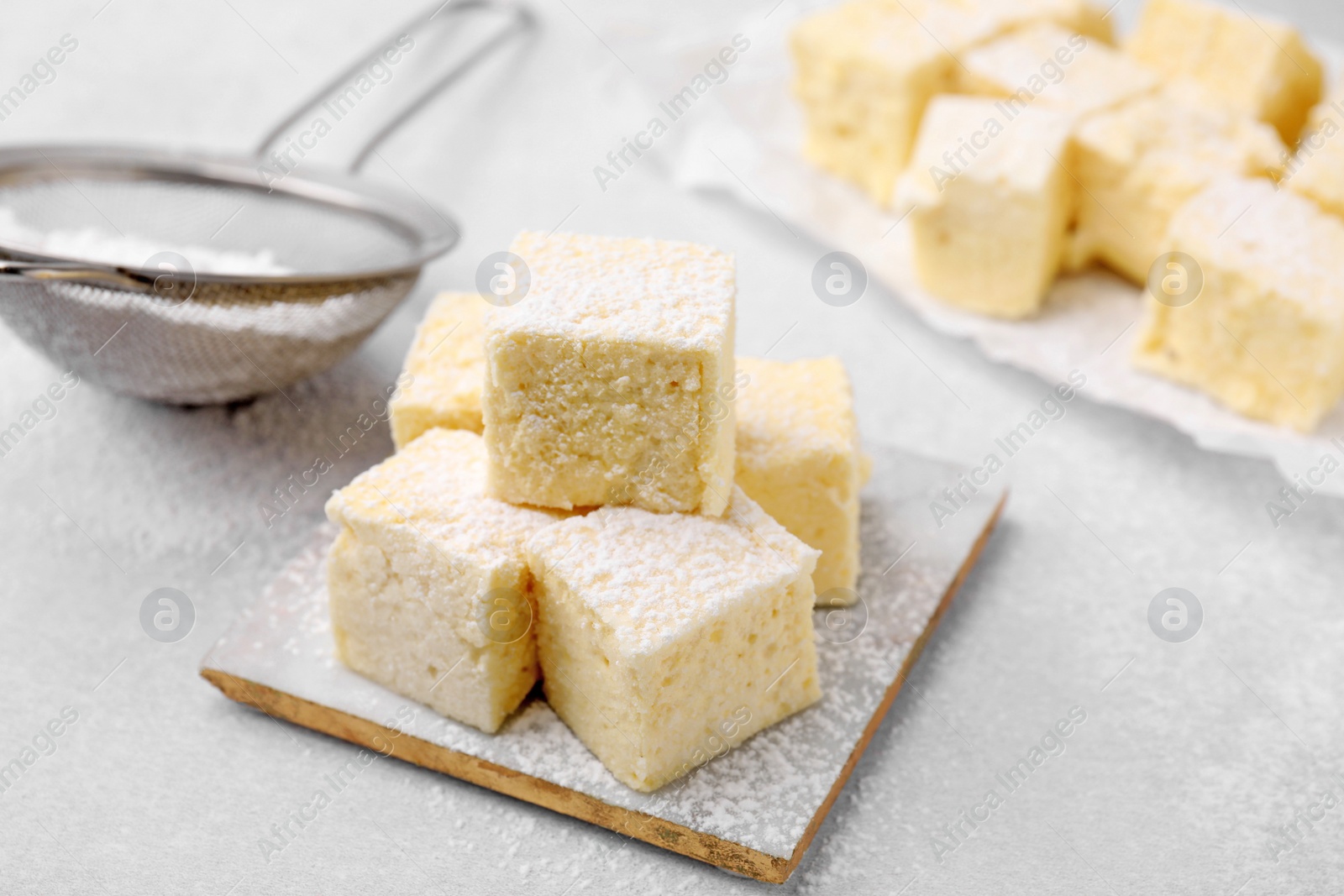 Photo of Delicious sweet marshmallows with powdered sugar on light grey table