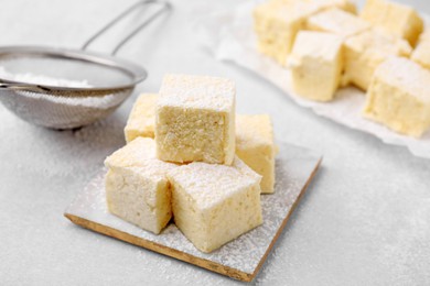 Photo of Delicious sweet marshmallows with powdered sugar on light grey table