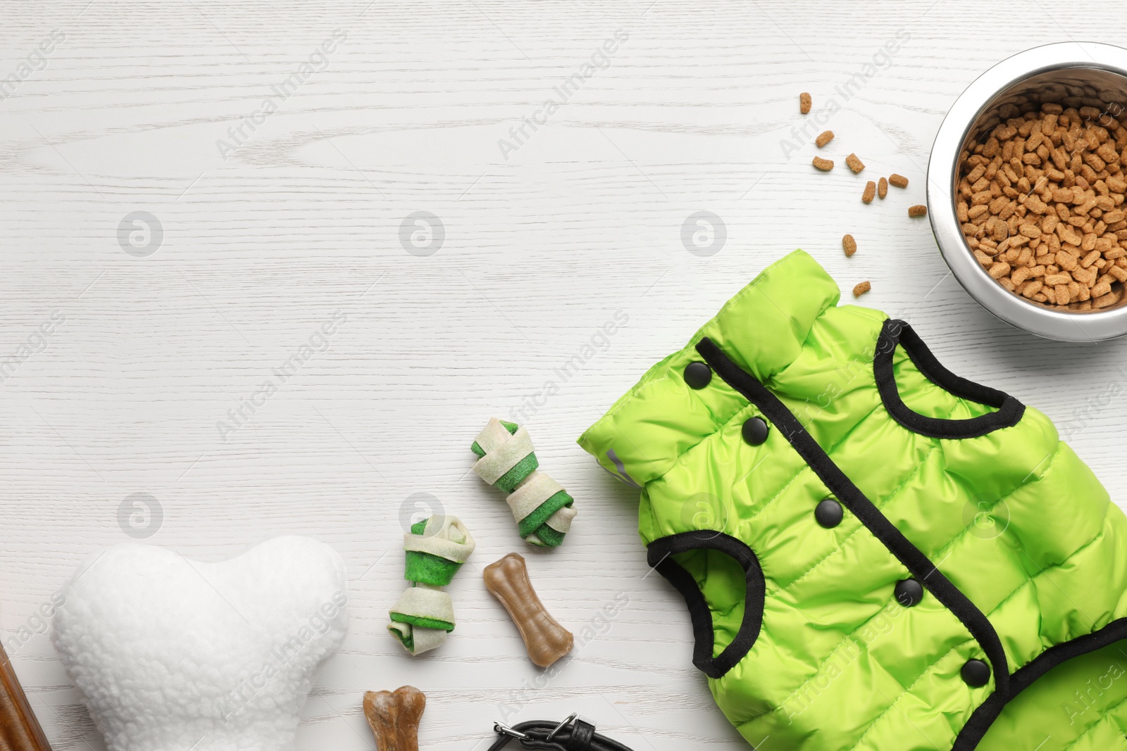 Photo of Flat lay composition with dog clothes, food and accessories on white wooden table. Space for text