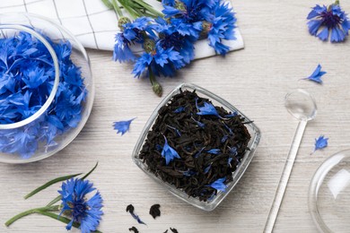 Photo of Composition with dry tea leaves and cornflowers on white wooden table, flat lay