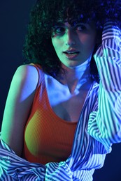 Beautiful young woman posing on color background in neon lights