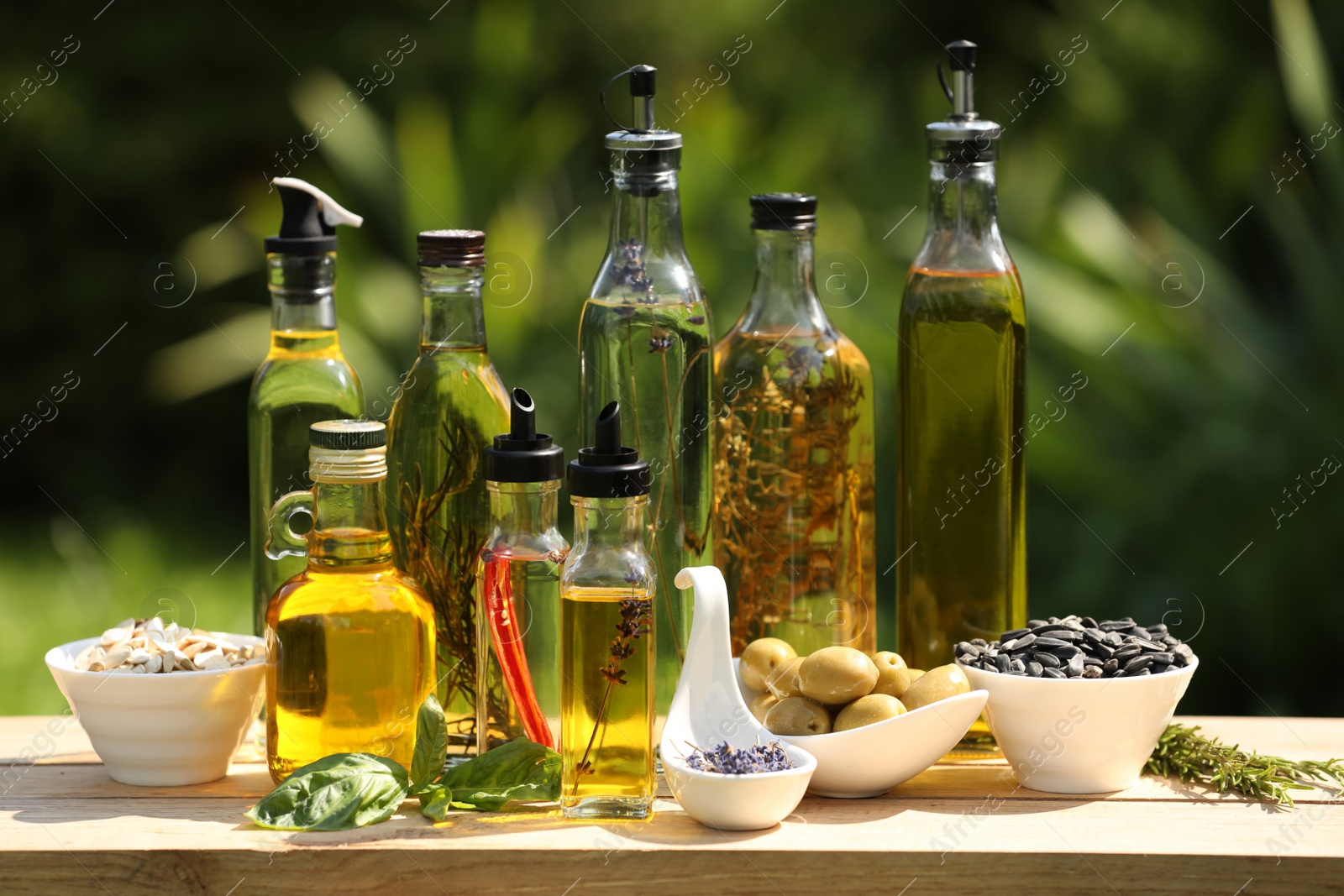 Photo of Different cooking oils and ingredients on wooden table against blurred green background