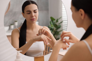 Photo of Woman with dry skin looking at mirror in bathroom