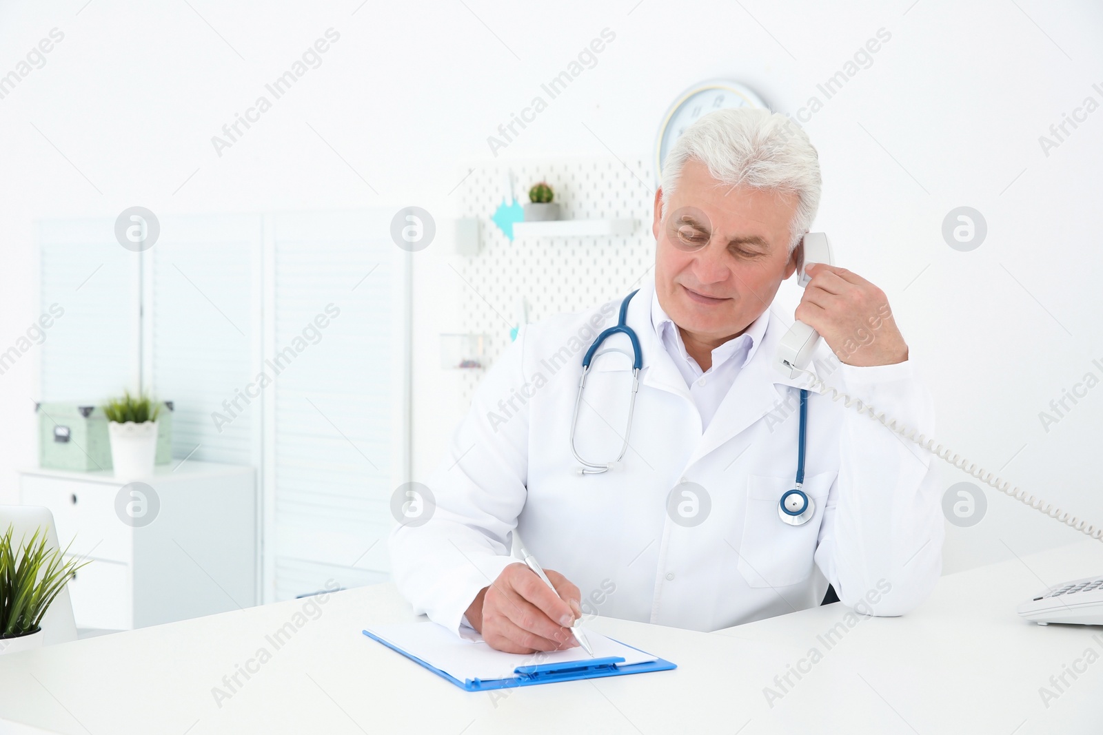 Photo of Senior male doctor working at reception desk in hospital