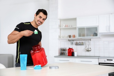 Photo of Young athletic man preparing protein shake in kitchen, space for text
