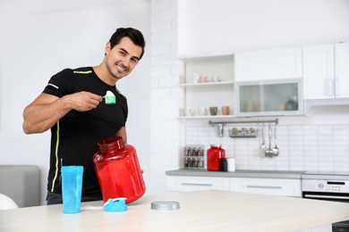 Young athletic man preparing protein shake in kitchen, space for text