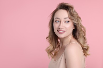 Photo of Portrait of smiling woman on pink background. Space for text