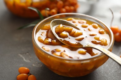 Photo of Delicious sea buckthorn jam in bowl on grey table, closeup