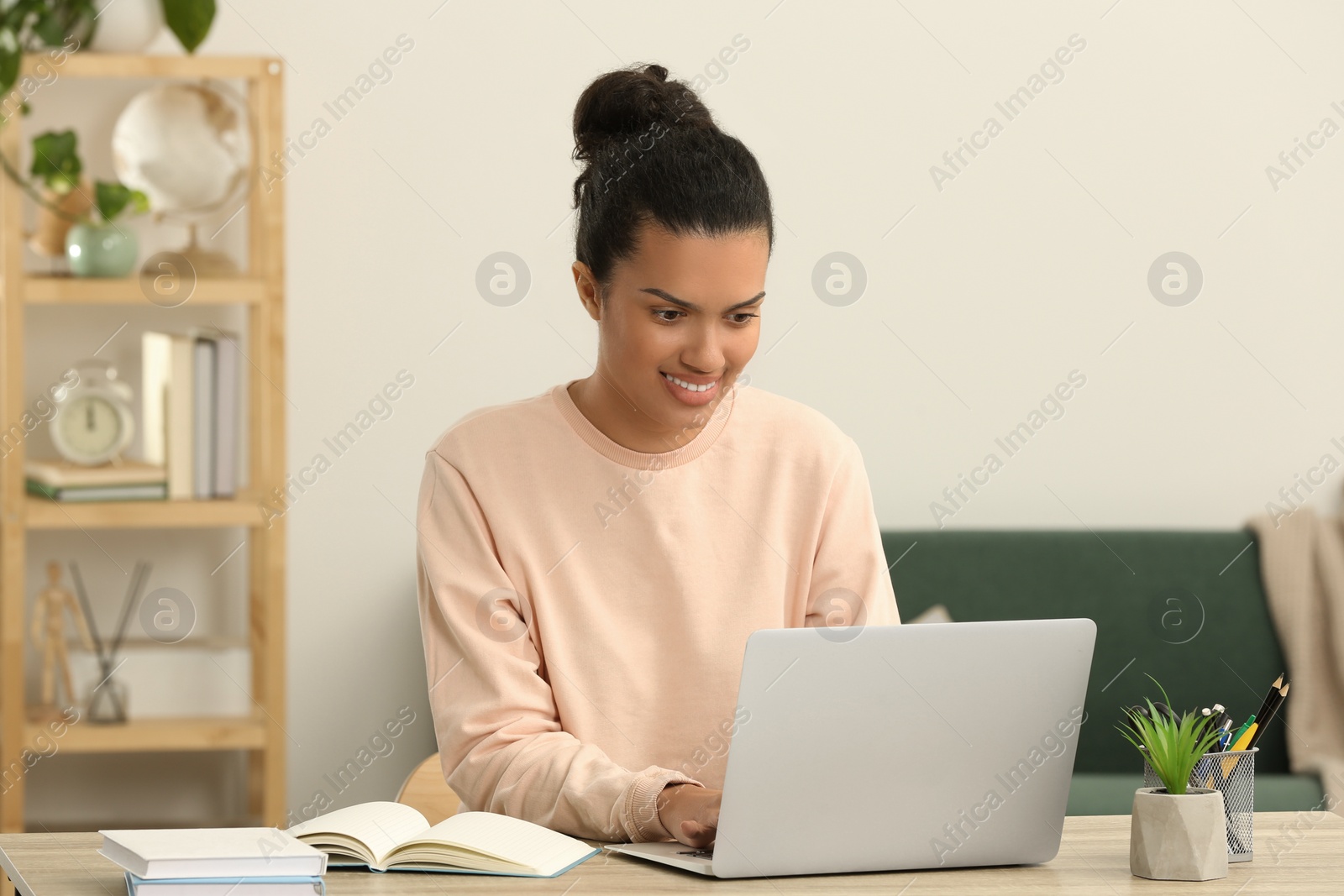 Photo of Beautiful African American woman working with laptop at table in room
