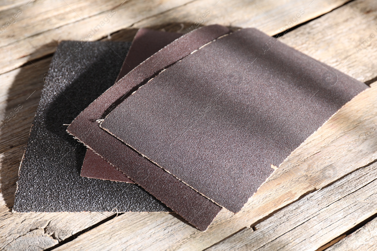 Photo of Many coarse sandpapers on wooden table, closeup