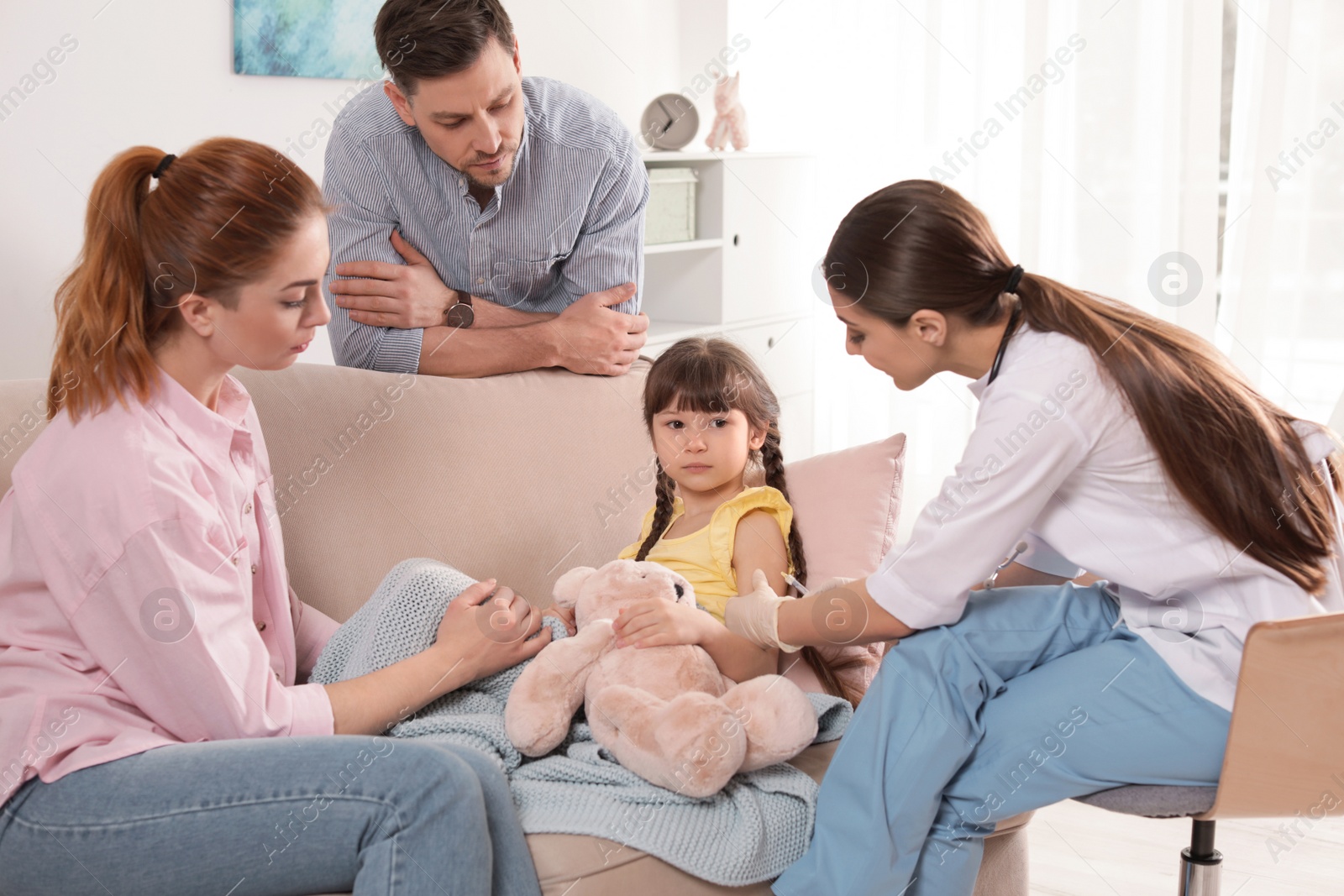 Photo of Family doctor vaccinating little child at home