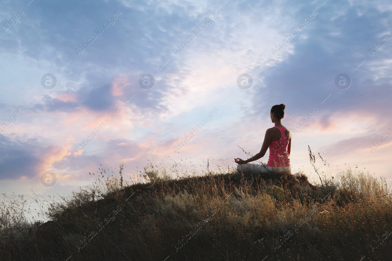 Photo of Woman meditating on hill near sea, back view. Space for text