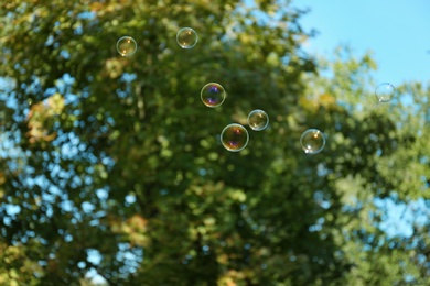 Photo of Beautiful translucent soap bubbles outdoors on sunny day. Space for text