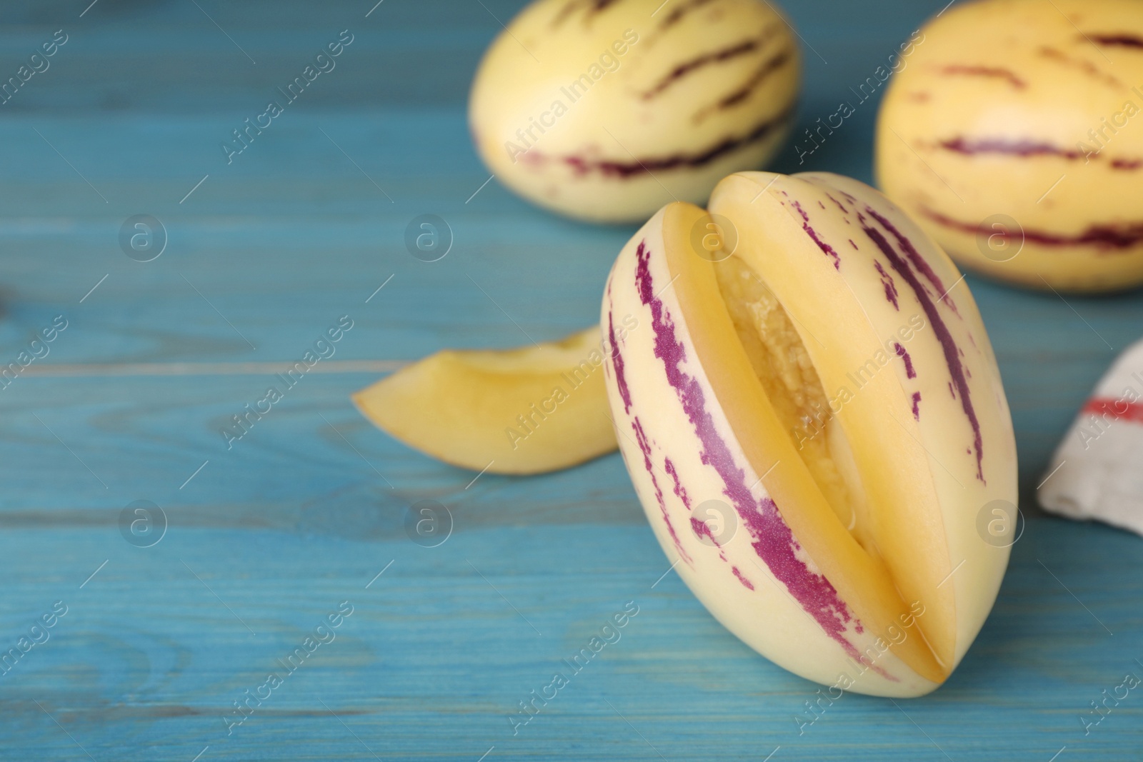 Photo of Cut  pepino melon on light blue wooden table, closeup. Space for text