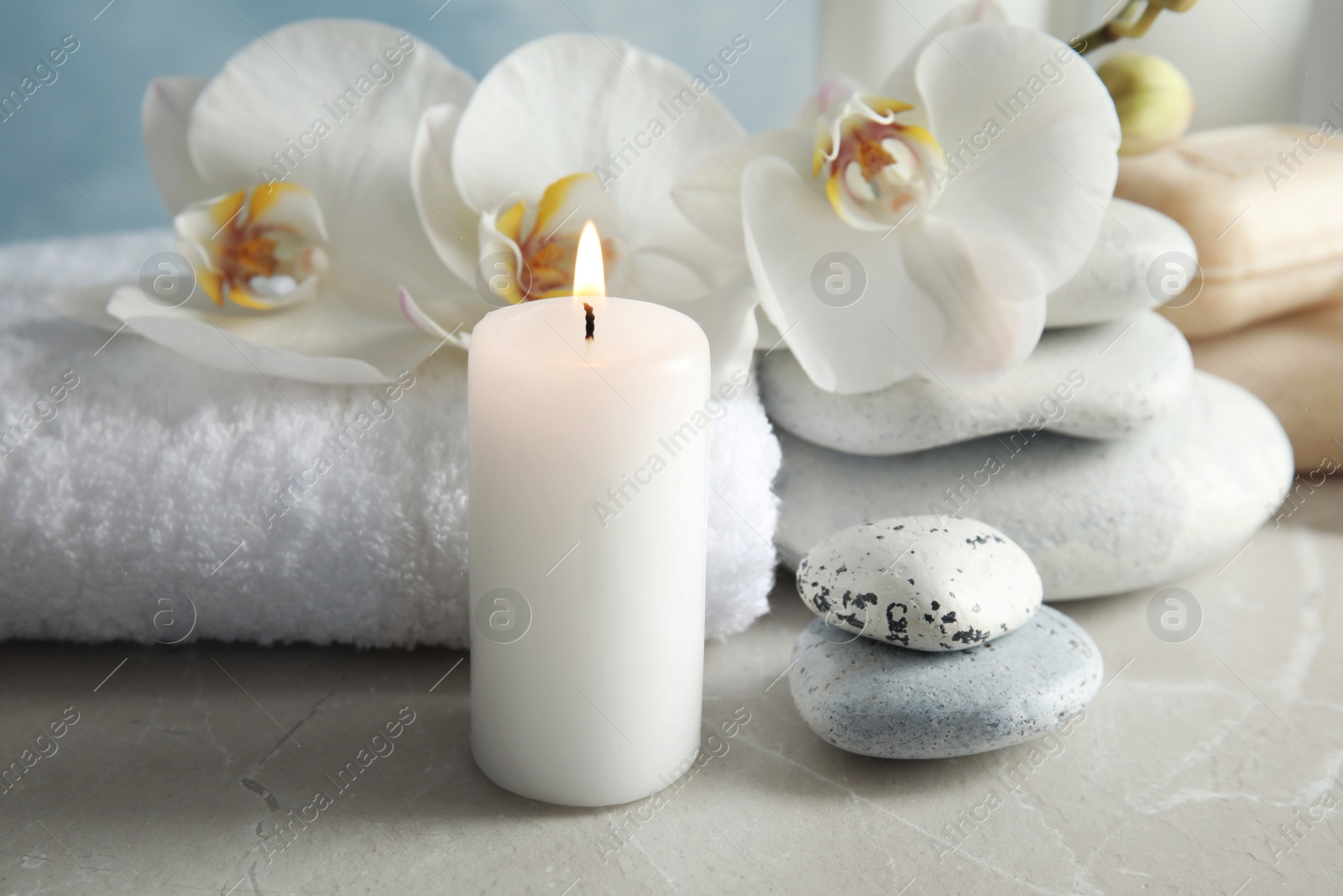 Photo of Beautiful composition with candle and spa stones on light table