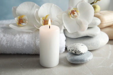 Photo of Beautiful composition with candle and spa stones on light table