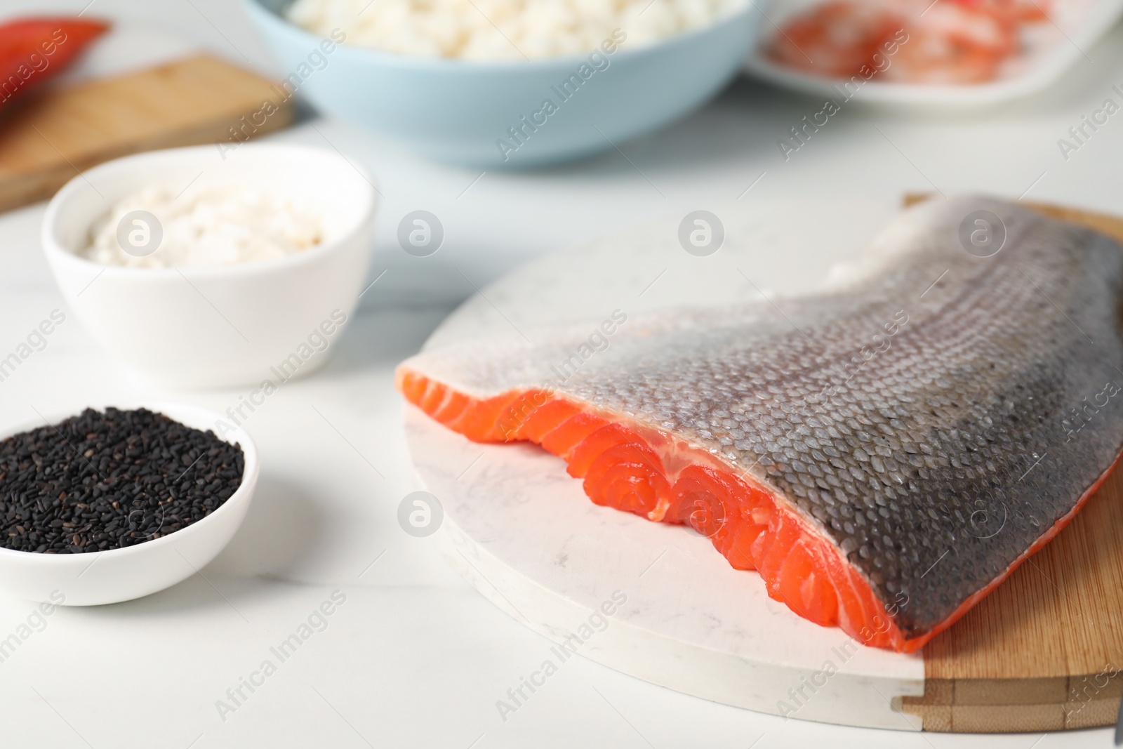 Photo of Fresh salmon and other ingredients for sushi on white marble table, closeup