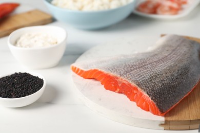 Fresh salmon and other ingredients for sushi on white marble table, closeup