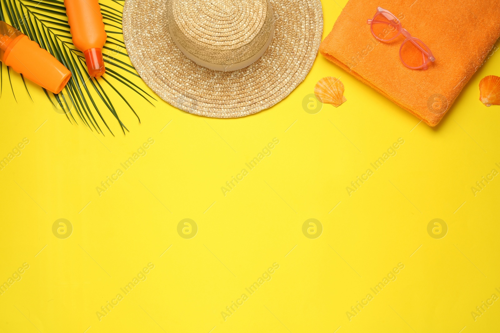 Photo of Beach towel, straw hat, sunglasses and sun protection products on yellow background, flat lay. Space for text