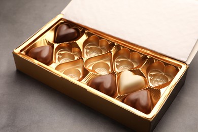 Photo of Partially empty box of chocolate candies on grey table, closeup