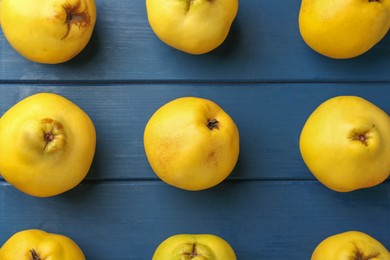Photo of Tasty ripe quinces on blue wooden table, flat lay