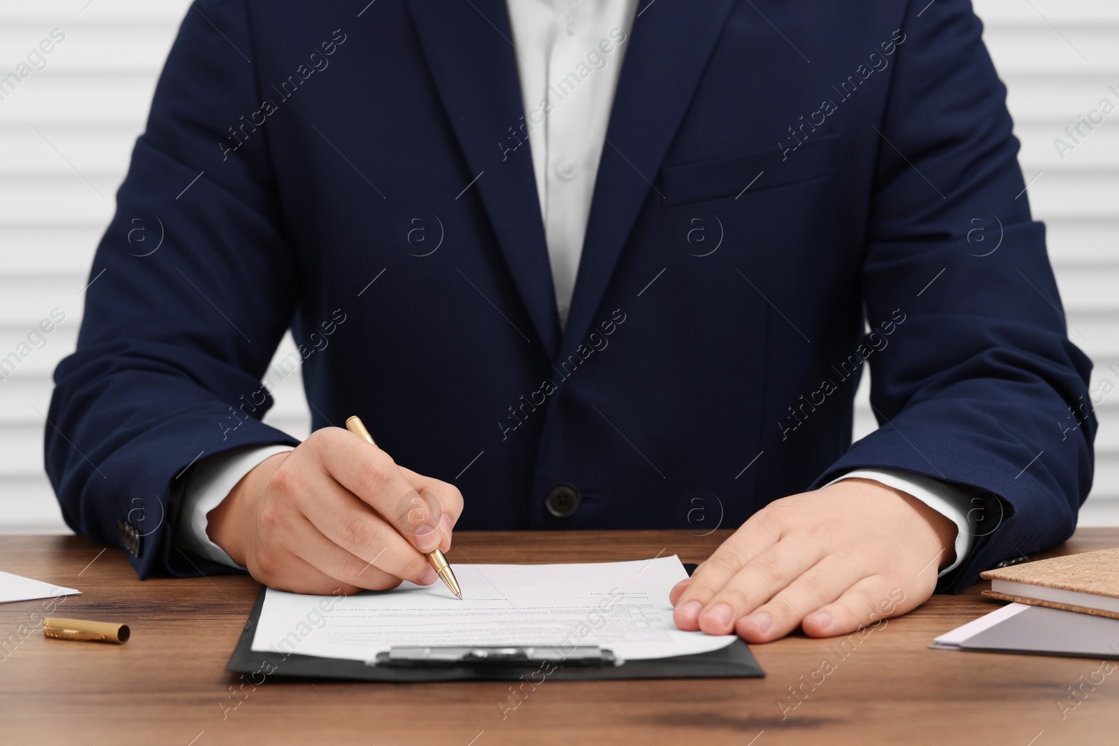 Photo of Man signing document at wooden table, closeup