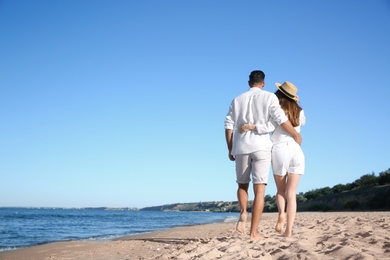 Photo of Lovely couple walking on beach, back view. Space for text