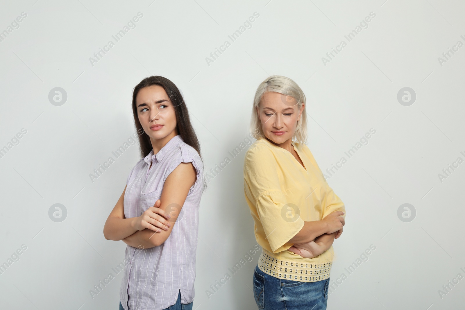 Photo of Portrait of young woman and her mother-in-law on white background. Family quarrel