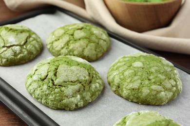 Photo of Baking tray with tasty matcha cookies on table, closeup