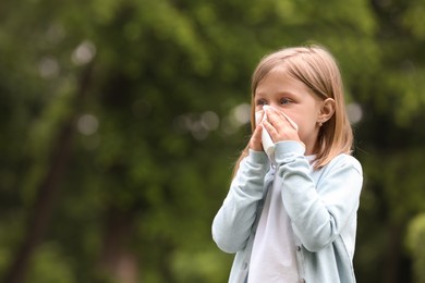 Photo of Little girl suffering from seasonal spring allergy outdoors, space for text