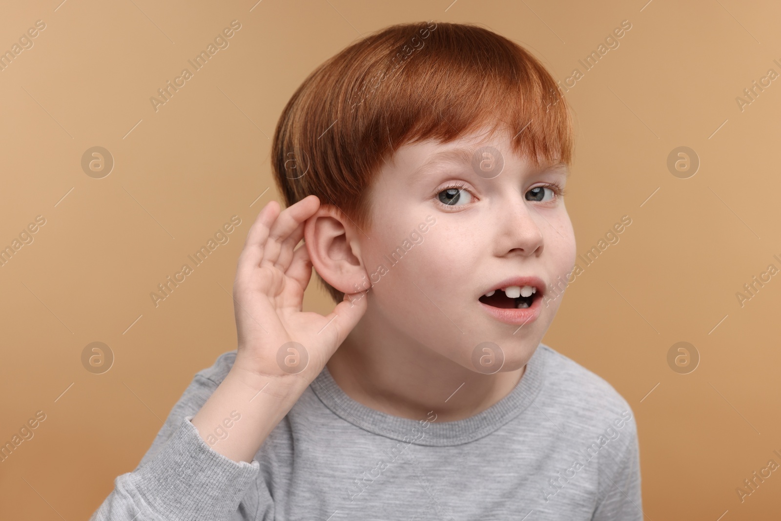 Photo of Little boy with hearing problem on pale brown background