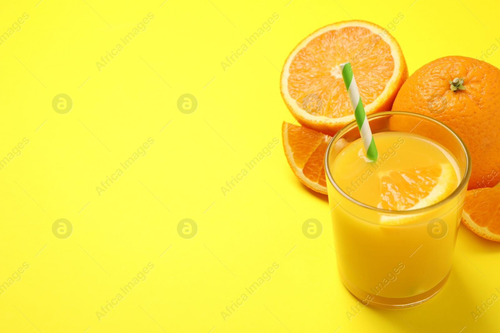 Photo of Glass of orange juice and fresh fruits on yellow background. Space for text