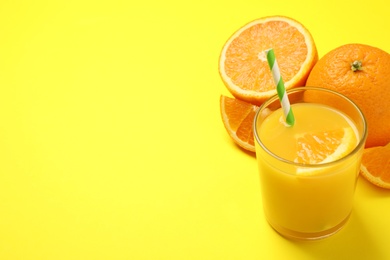 Photo of Glass of orange juice and fresh fruits on yellow background. Space for text