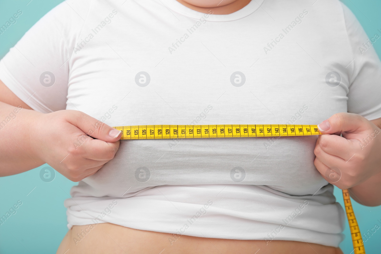 Photo of Overweight woman with measuring tape on color background