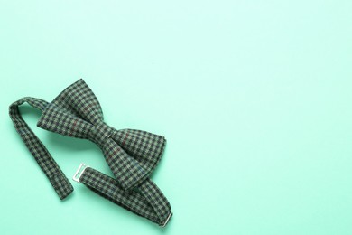 Photo of Stylish gingham bow tie on light green background, top view. Space for text