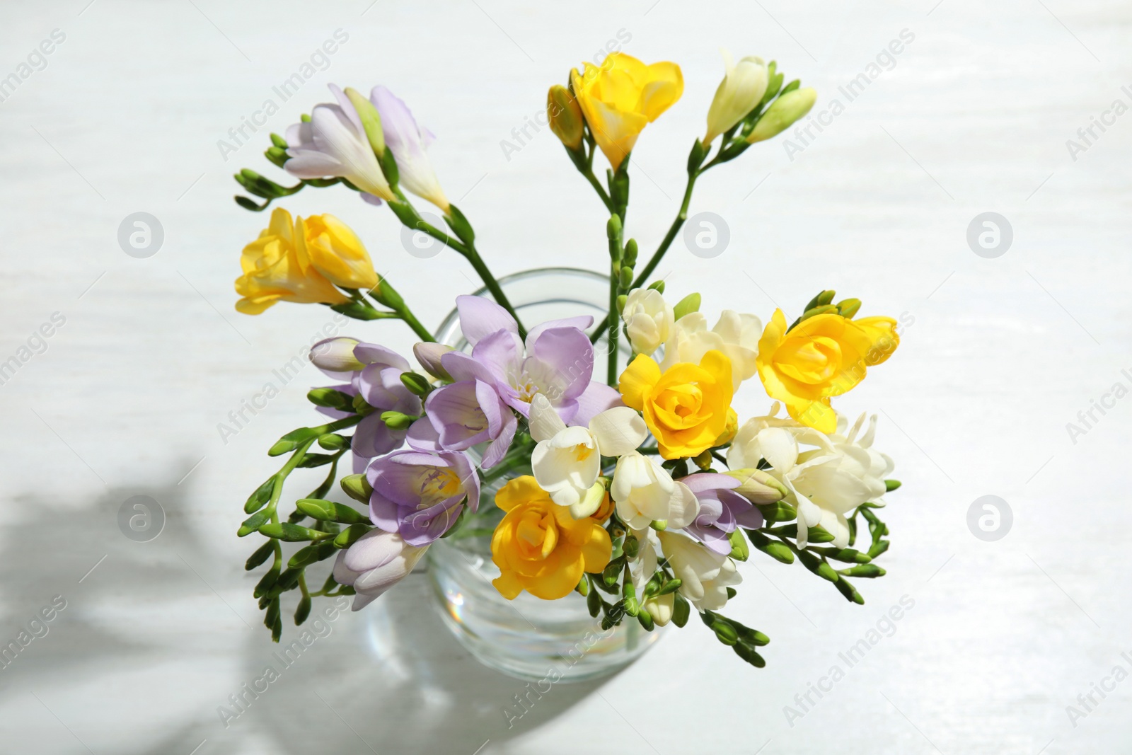 Photo of Bouquet of fresh freesia flowers in vase on table, above view