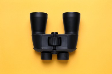 Photo of Modern binoculars on orange background, top view