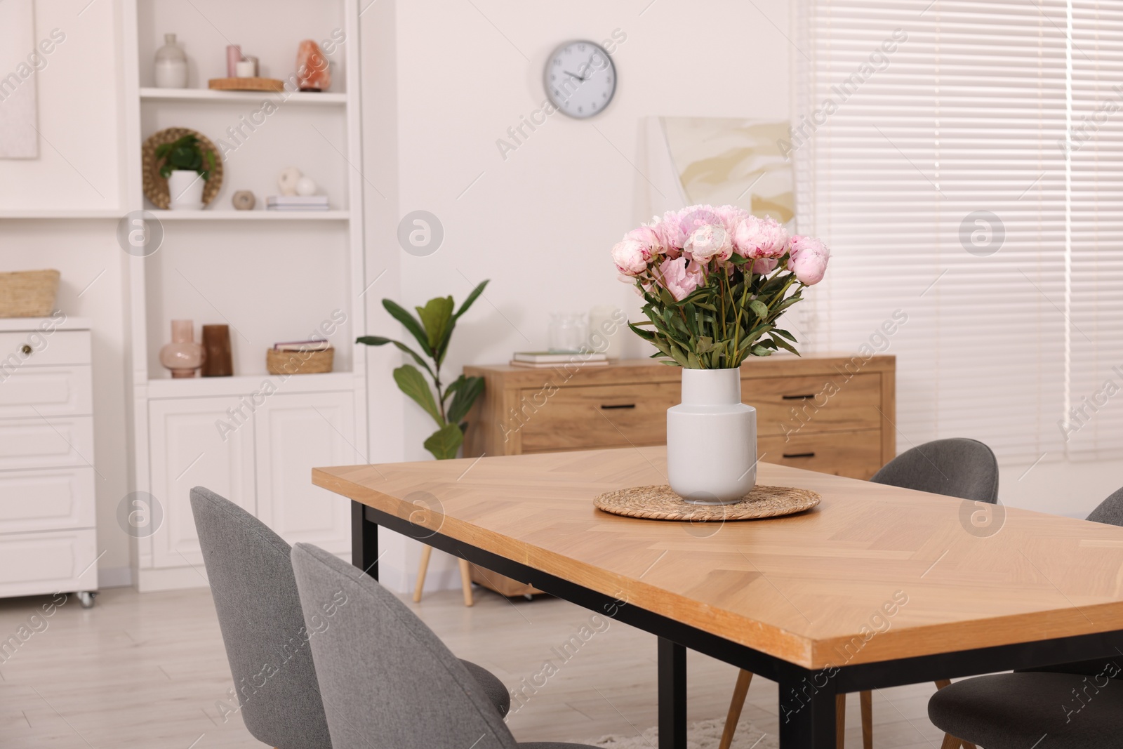 Photo of Stylish dining room with cosy furniture and flowers