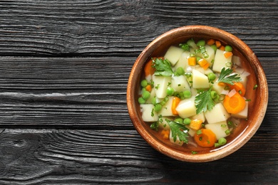 Bowl of fresh homemade vegetable soup on dark wooden background, top view. Space for text