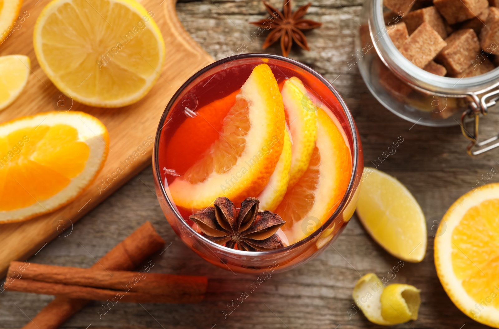 Photo of Aromatic punch drink and ingredients on wooden table, flat lay