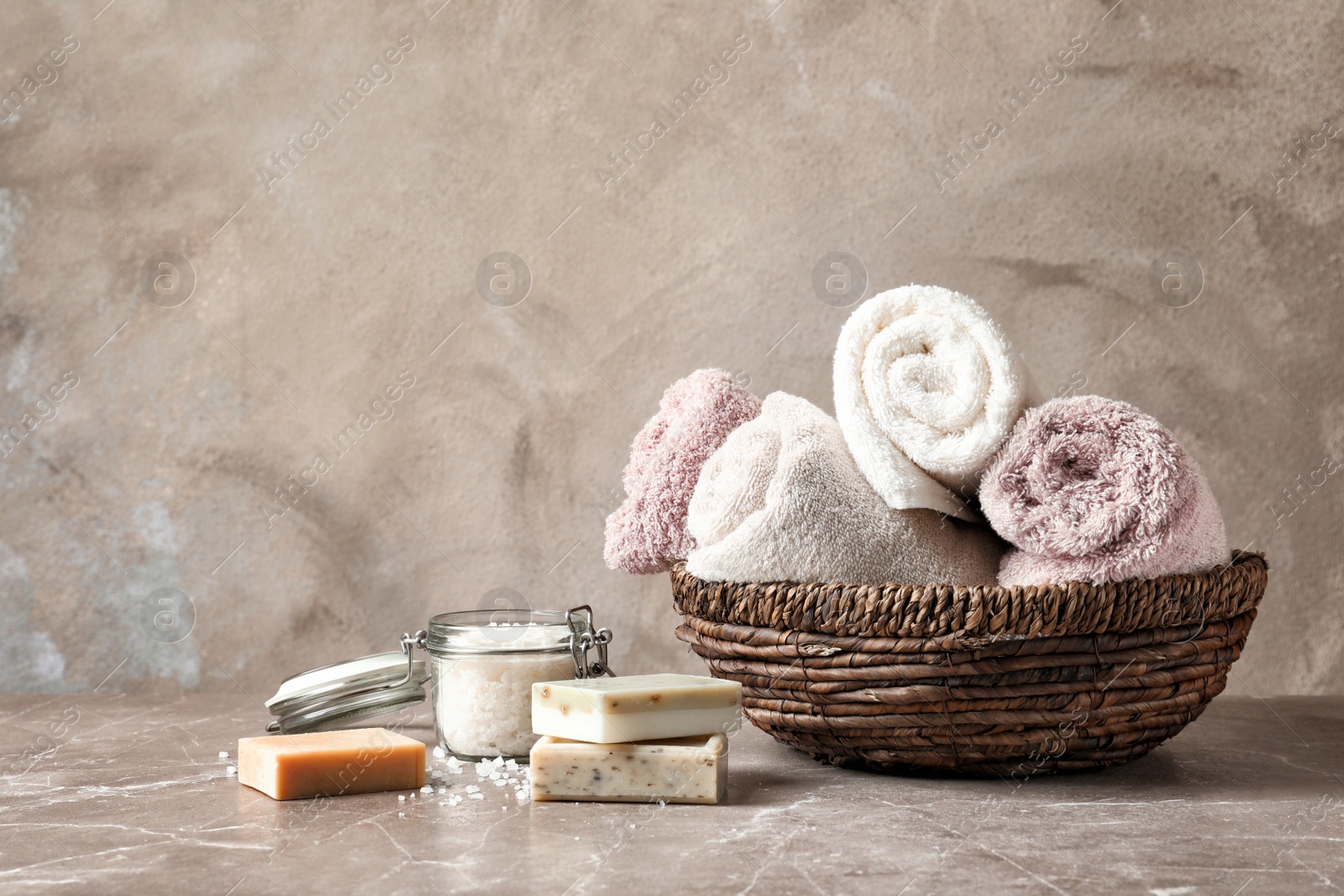 Photo of Basket with clean towels, soap and sea salt on table