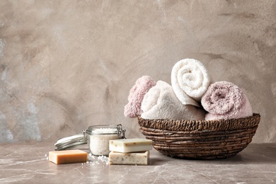 Basket with clean towels, soap and sea salt on table