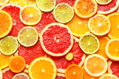 Photo of Slices of fresh citrus fruits as background, top view